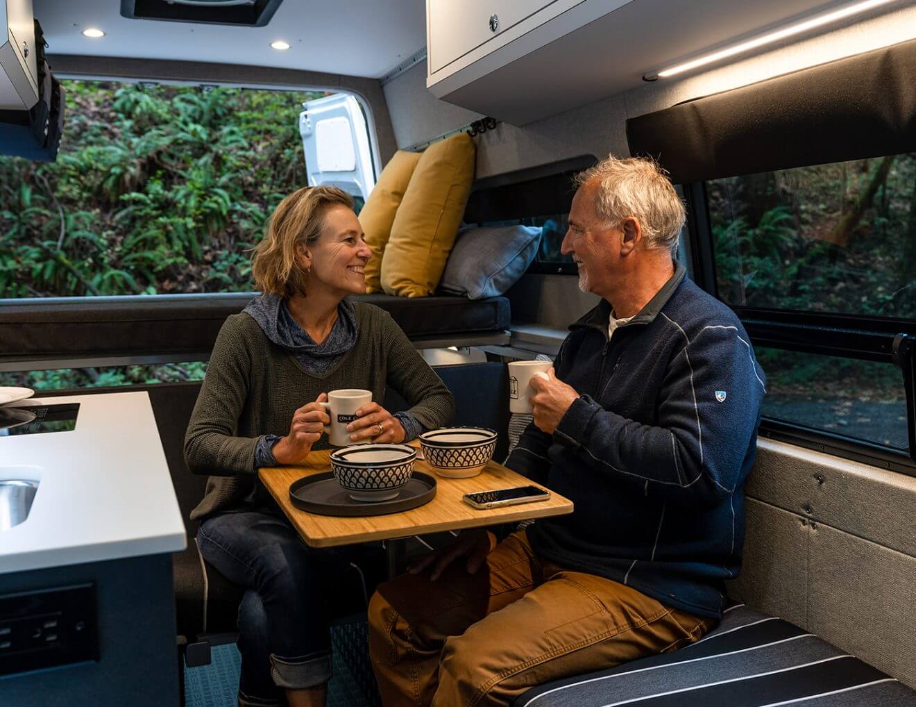 Couple sits at interior dinette with removable table sharing a beverage