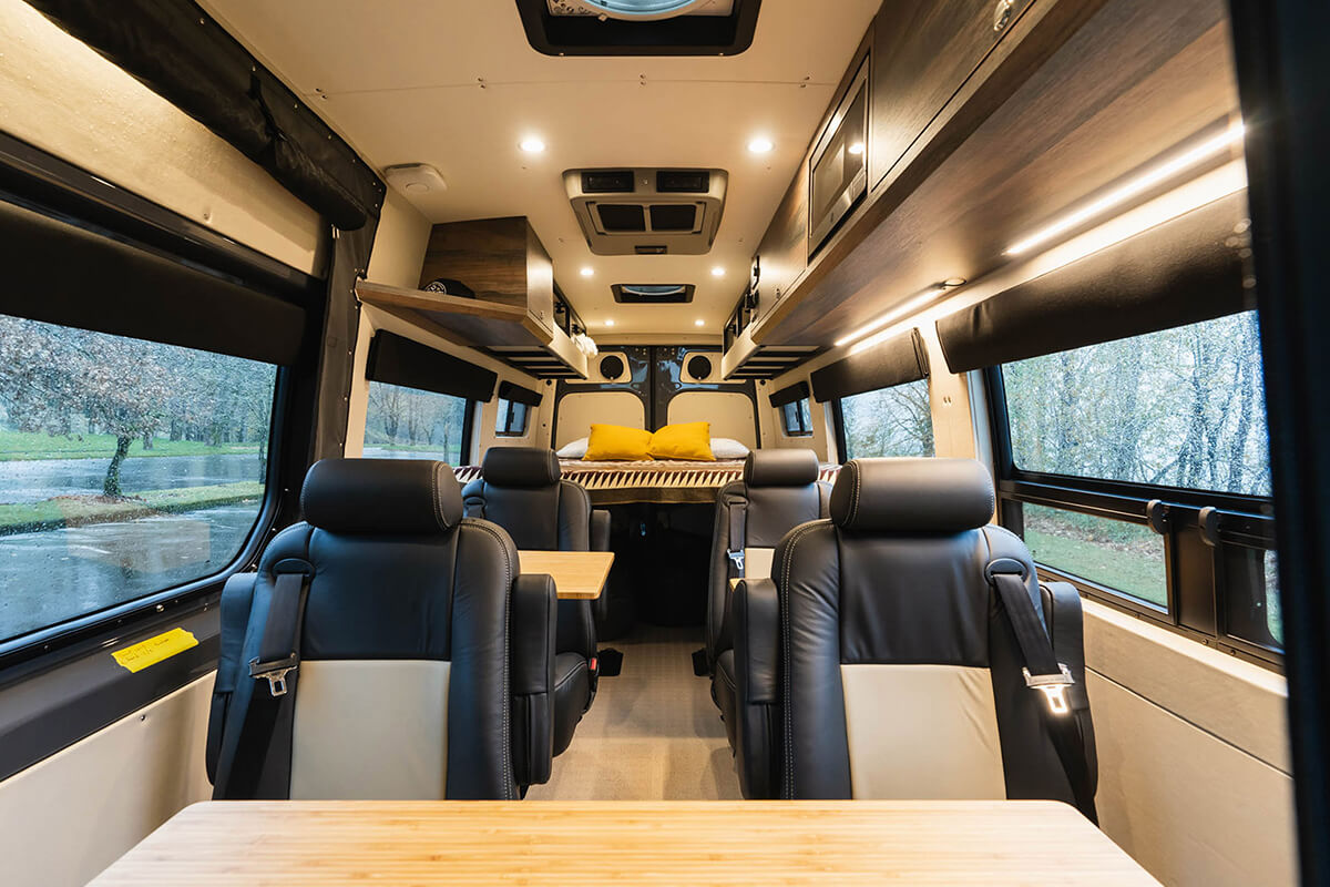 Van interior with two rows of two removable dot-approved captain's chairs and a removable table