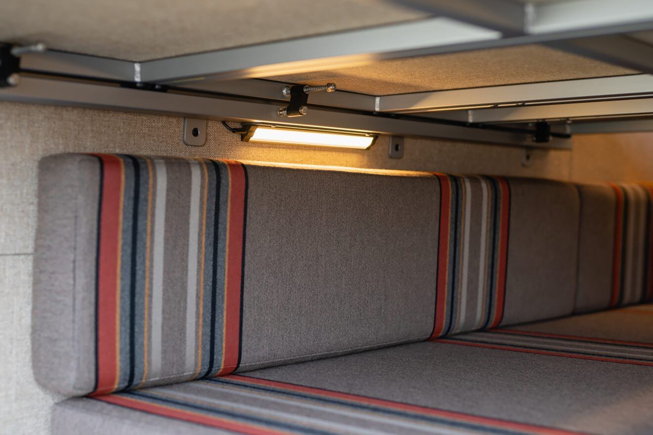 Custom pinstripe upholstery across dual bench seats next to LED load lights