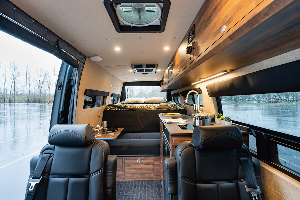 Interior van with two removable captain's chairs in front of a galley kitchen