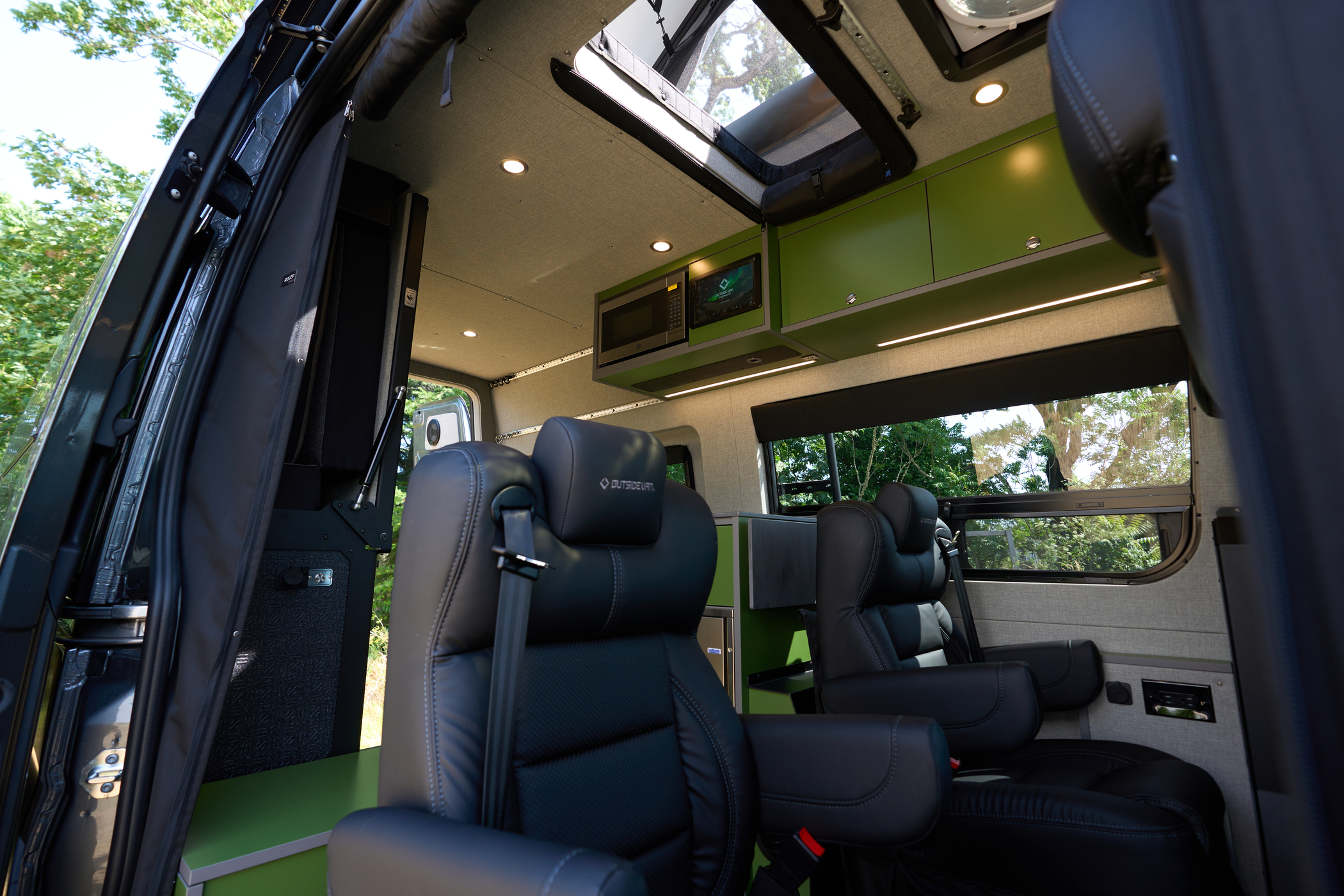 Interior view of the passenger seats in the Outside Van Overnight with view of rooftop tent entrance visible.