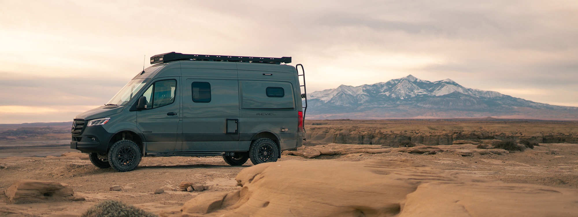 Winnebago van in a desert mountain scene with overcast skies.